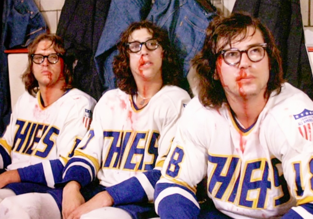 The movie "Slap Shot", directed by George Roy Hill. Seen here of the Charlestown Chiefs hockey team, the Hanson Brothers. From left, David Hanson (as Jack Hanson). Steve Carlson (as Steve Hanson), Jeff Carlson (as Jeff Hanson). Initial theatrical release February 25, 1977. Screen capture. Copyright © 1977 Universal Pictures. Credit: © 1977 Universal Pictures / Courtesy: Pyxurz.